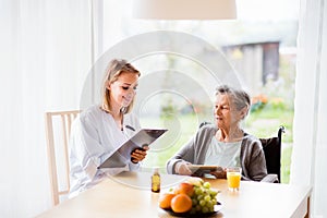 Health visitor and a senior woman with tablet.