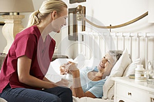 Health Visitor Talking To Senior Woman Patient In Bed At Home