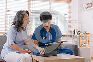 A health visitor is using a tablet to explain to a sick elderly woman how to take her pills.The visitor is taking