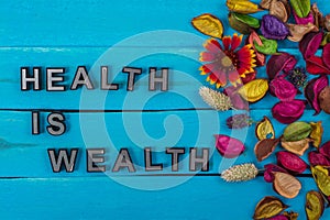 Health is wealth text on blue wood with flower