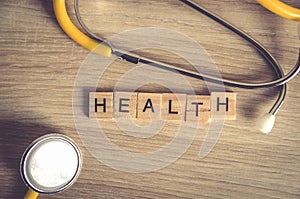 Health word background on wood blocks with yellow stethoscop on wood background , top view ,healthy concept photo