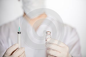 Health worker holding syringe and vial with vaccine against COVID-19, measles and flu