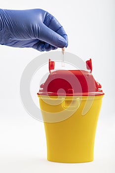 Health worker throws sharp waste into the medical waste bin. Medical waste bin pocket size 0,4 liter. Yellow biohazard medical