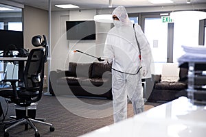 Health worker wearing protective clothes cleaning the office using disinfectant photo