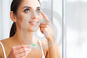 Health. Young Girl Holds Contact Lens In Hands. Portrait of a Beautiful Woman with Green Eyes and Contact Lenses