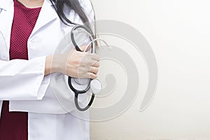 Healthcare background concept. Closeup doctor holding stethoscope standing on white wall with empty space.