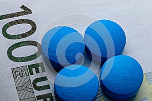 Healthcare. Blue tablets pill macro on 100 euro bill. Drug abuse