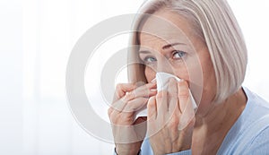 Healthcare, cold, allergy and people concept, sick woman blowing her runny nose in paper tissue on white background