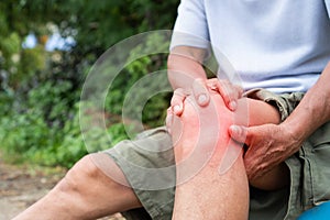 Healthcare concept. Asian Older man suffering from knee pain sitting on chair. Health problem retired asian old man hands touching