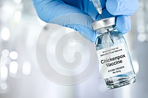 Healthcare concept with a hand in blue medical gloves holding Chicken pox vaccine vial photo