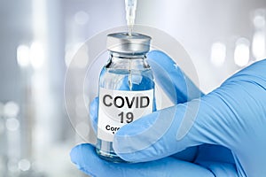 Healthcare concept with a hand in blue medical gloves holding Coronavirus, Covid 19 virus, vaccine vial