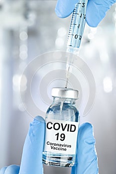 Healthcare concept with a hand in blue medical gloves holding Coronavirus, Covid 19 virus, vaccine vial