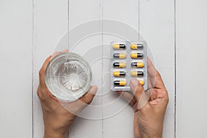 Healthcare Concept with Hand Holding Water and Pills on White Wooden Table