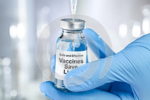 Healthcare concept with a hand in medical gloves holding a vaccine vial wtih the words Safe and Effective, Vaccines Save