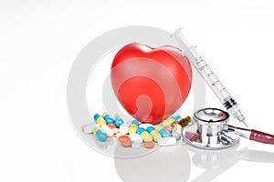 Healthcare concept with medicine pills, caplet, tablet, capsule and red heart, stethoscope, syringe as prop