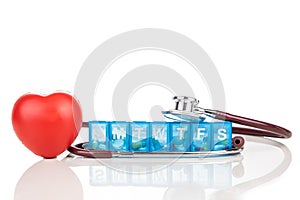 Healthcare concept with pill organizer box for storing doses of daily medicine, with red heart and stethoscope as prop