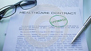 Healthcare contract approved, officials hand stamping seal on business document