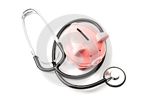 Healthcare cost and the high price of quality health care insurance concept theme with a stethoscope and a pink piggy bank