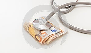 Healthcare cost. Medical stethoscope on Euro banknote stack isolated on white, close up