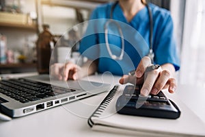 Healthcare costs and fees concept.Hand of smart doctor used a calculator and smartphone, tablet for medical costs at hospital