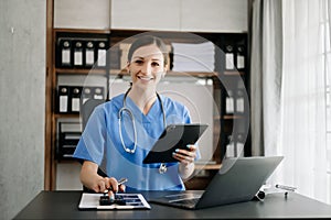 Healthcare costs and fees concept.Hand of smart doctor used a calculator and smartphone, tablet for medical costs at hospital in