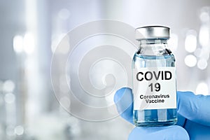 Healthcare cure concept with a hand in blue medical gloves holding Coronavirus, Covid 19 virus, vaccine vial