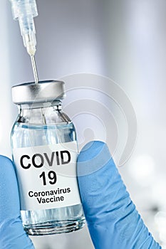 Healthcare cure with a hand in blue medical gloves holding Coronavirus, Covid 19 virus, vaccine vial