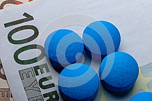 Healthcare expences. Blue tablets pill macro on 100 euro bill. Drug abuse