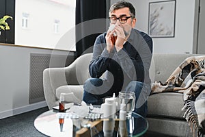 healthcare, flu, hygiene and people concept - sick senior man with paper wipe blowing his nose at home