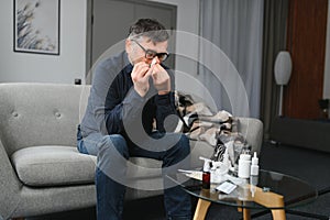 healthcare, flu, hygiene and people concept - sick senior man with paper wipe blowing his nose at home