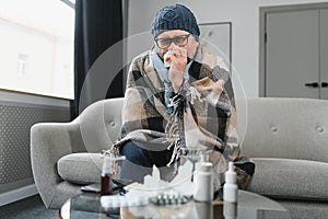 healthcare, flu, hygiene and people concept - sick senior man with paper wipe blowing his nose at home