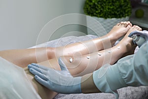 Healthcare Ideas. Professional Beautician Applying Soothing Cream on Female`s Legs After Wax Depilation Procedure In Spa Salon