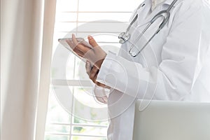 Healthcare medical concept : Asian woman Doctor standing using tablet computer with white gown suite and wearing Stethoscope on