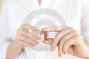 Healthcare and medical concept. Close-up view of woman holding pill in one hand and glass of water in the another hand. Focus on