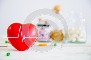 Healthcare and medical concept. Red heart on wooden table with set of medicine bottles and medicine pills background.