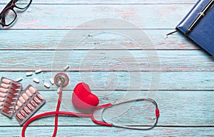 Healthcare and medical concept red stethoscope and medicine on the blue wooden background