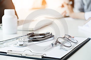 Healthcare and Medical concept, View of stethoscope and equipment on foreground table with patient listening intently to a female