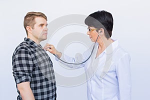 Healthcare, medical exam, people and medicine concept - young man and doctor with stethoscope listening to heartbeat