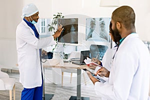 Healthcare, medical: Group of African doctors discuss and looking x-ray in a clinic or hospital. African man chief