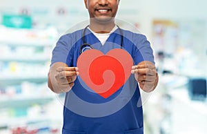 doctor or male nurse with red heart at pharmacy