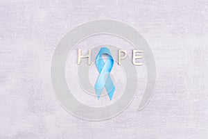 Healthcare and medicine concept - blue prostate cancer awareness ribbon and word hope made of wooden letters, achalasia and photo