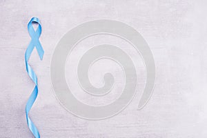 Healthcare and medicine concept - blue ribbon of prostate cancer awareness, achalasia and adrenocortical cancer, on gray photo