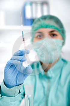 Healthcare and medicine concept - female doctor in mask holding syringe with injection.toned image