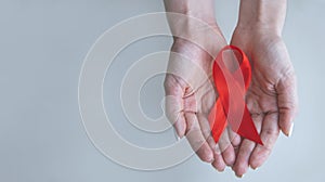 healthcare and medicine concept - female hands holding red AIDS awareness ribbon