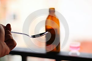 Healthcare and medicine concept - Spoon next to a cough syrup