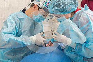 Healthcare, medicine. Young woman with dentist in mask with loupe binoculars in a dental surgery.