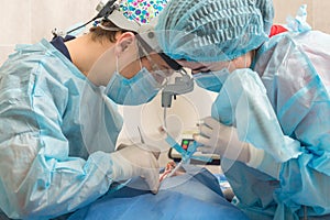 Healthcare, medicine. Young woman with dentist in mask with loupe binoculars in a dental surgery.