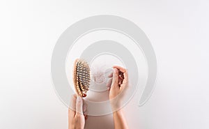 Healthcare problem concept. Woman hand holding hair loss or hair fall in comb on white background