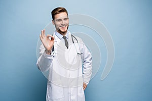 Healthcare, profession, gesture, people and medicine concept - smiling male doctor in white coat showing ok hand sign.