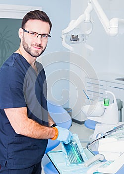 Healthcare, profession, stomatology and medicine concept - smiling male dentist over medical office background